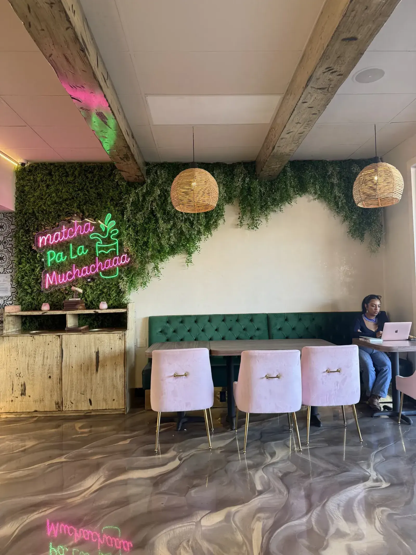 Inside Canela Café: a green wall, a neon sign and pink chairs