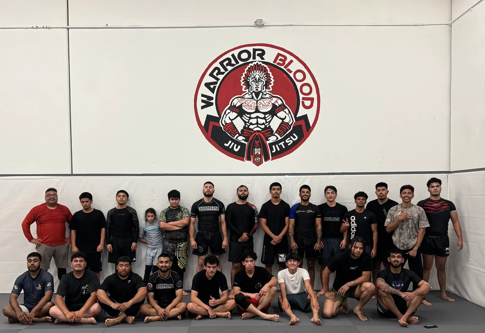 The Warrior Blood team lined up on the mat under the gym's logo